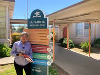 Community Health Worker Gloria Torres stands in front of a sign at the Maple Neighborhood Center, run by the La Familia Counseling Center, in Sacramento on April 10, 2023.