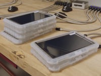 Tablet computers, encased in thick plastic coverings, charge on a table.