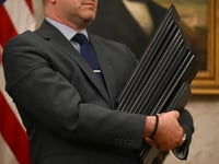 An aide holds executive orders to be signed by President Trump at the White House on Monday.