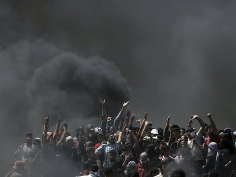 Palestinian protesters chant slogans as they burn tires during a protest on the Gaza Strip's border with Israel, Monday, May 14, 2018. 