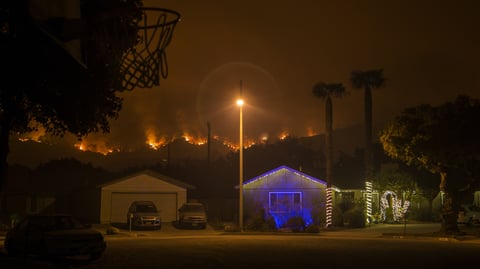 Christmas decorations illuminate a house as the growing Thomas Fire advances toward Santa Barbara County seaside communities.