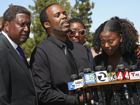 Civil rights attorney John Burris, left, listens as parents Marcus Robinson, center, and Tanisha Porter speak during a media conference on Wednesday, July 18, 2018, in Fairfield, Calif.
