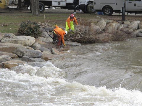 City crews clear tree branches and debris from the Truckee River in downtown Reno, Nev., Tuesday, Jan. 10, 2017, after flooding sent water over the banks and caused to close all downtown bridges the day before.
