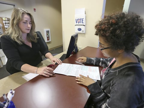 Sabine Kamagou, 19, right, gets help filling out voter registration form from Sacramento County Registrar of Voters employee, Cyndi Morrison, in Sacramento, Calif.