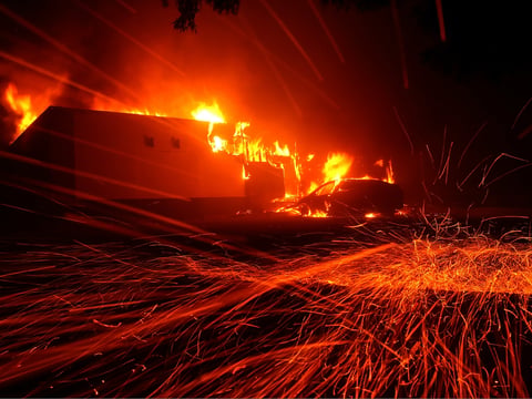 Embers blow in the wind as the Camp Fire burns a KFC restaurant in Paradise on November 8, 2018.