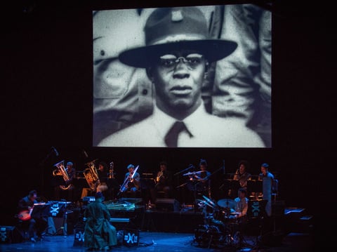 A photograph of jazz pianist James Reese Europe projected above the musicians performing Jason Moran's James Reese Europe and the Absence of Ruin.