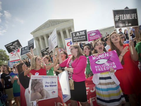 Demonstrators outside the U.S. Supreme Court in Washington, D.C., in 2014 react to hearing the court's decision on the Hobby Lobby birth control case.