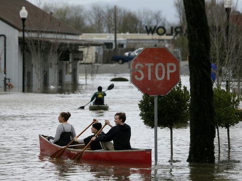 People paddle and row through the flooded Barlow Market District Wednesday, Feb. 27, 2019, in Sebastopol, Calif.