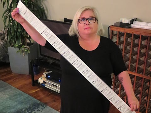 Carol Dahmen poses with a receipt that's more than 4 feet long—for the purchase of a single item.