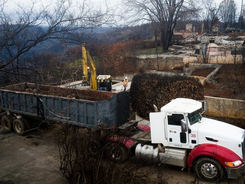 In this Feb. 8, 2019 file photo, an excavator loads debris onto a truck while clearing a property burned by the Camp Fire in Paradise, Calif.