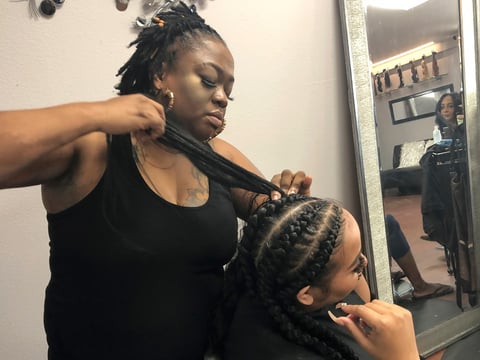 Elicia Drayton, left, braids the hair of Shereen Africa at Exquisite U hair salon in Sacramento on July 3, 2019. California is the first state to ban job and school discrimination against people for wearing natural hair styles such as braids.