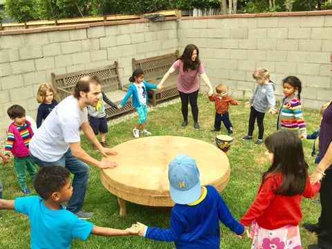 Children at Little Stars Preschool and Family Childcare in Los Angeles dance at a drum circle with the school’s owner/director Darlene Morales, at top in the pink t-shirt.