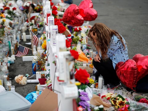 Gloria Garces kneels in front of crosses at a makeshift memorial near the scene of a mass shooting at a shopping complex Tuesday, Aug. 6, 2019, in El Paso, Texas.