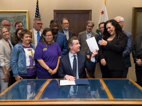 Assemblywoman Lorena Gonzalez, right, and AB 5 proponents celebrate as Gov. Gavin Newsom signs the legislation, which forces companies to treat roughly 1 million contract workers as employees under California law.