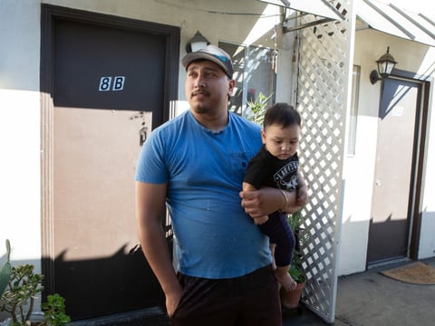 Alex Espinoza stands outside of his unit at Canal Farm Gardens with his 10-month-old son. He's been renting this apartment for more than five years, but following an eviction notice, will be forced to leave.