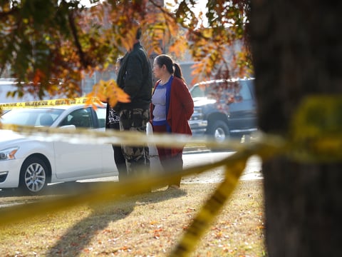 Yia Lee watches police investigate her neighbor's house on Lamona Ave. where a shooting took place at a house party which involved multiple fatalities and injuries in Fresno, Calif., Monday, Nov. 18, 2019.
