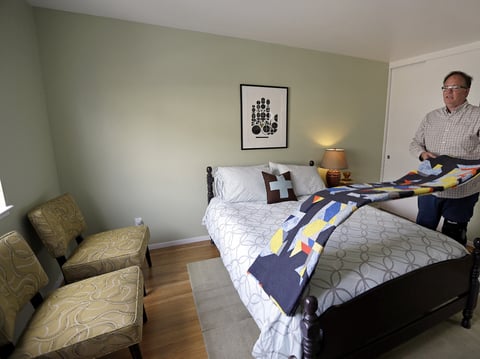 In this Oct. 16, 2015 file photo, Bruce Bennett folds a blanket in a room that he makes available to rent in he and his husband's home in San Francisco.