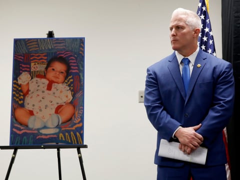 Yolo County District Attorney Jeff Reisig stands next to a photo of Kato Krow Perez, born in 2001, one of five infants believed to be killed by their father, during a news conference in Woodland, Calif., Monday, Jan. 27, 2020.