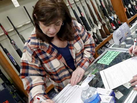 Andrea Schry (right) fills out the buyer's part of legal forms to buy a handgun as shop worker Missy Morosky fills out the vendor's parts after Dukes Sport Shop in New Castle, Pa., reopened on Wednesday.