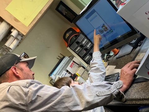 Campbell Construction and Engineering’s Jeff Campbell helps son Carter with school work in a trailer typically used for construction sites, but that is now being used as a daycare/school for the Campbell’s and two employees’ five children.