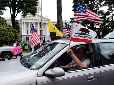 Demonstrators protesting California's stay at home order drive around the Calfornia state Capitol April 20, 2020.