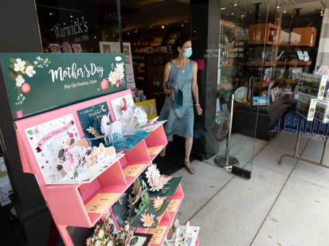 Nancy Warwick carries an order out of Warwick's Bookstore during curbside service Friday, May 8, 2020, in the La Jolla neighborhood of San Diego.