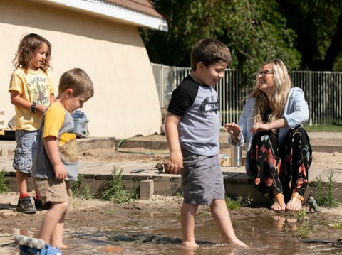 Amanda Simoni, owner of Heritage School of Discovery in Oakdale, laughs while students play in the school yard mud pit. A new California child care website aims to connect essential workers with available options.