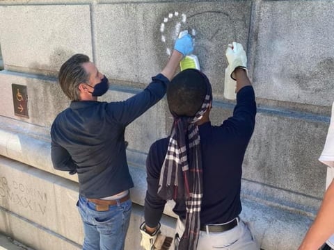 California Gov. Gavin Newsom and Stevante Clark clean up graffiti left by some protesters in downtown Sacramento on June 2, 2020.