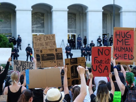 Demonstrators kneel at the east steps of the state Capitol. The crowd called for law enforcement officers on the steps to take a knee, but officers did not.