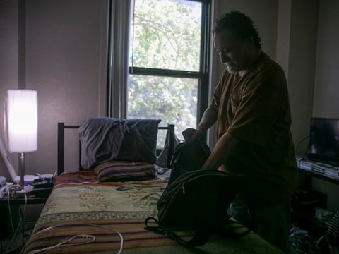 Salvador Bradford tidies his studio at Hotel Berry. Bradford has been living in the one-room unit for 8 months and spends most of his time watching movies and keeping his room organized.