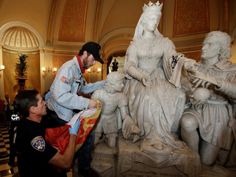 A demonstrator is removed from a statue in the rotunda of the Capitol, by a California Highway Patrol officer, during a protest by the Poor People's Campaign, Monday, June 4, 2018, in Sacramento, Calif.