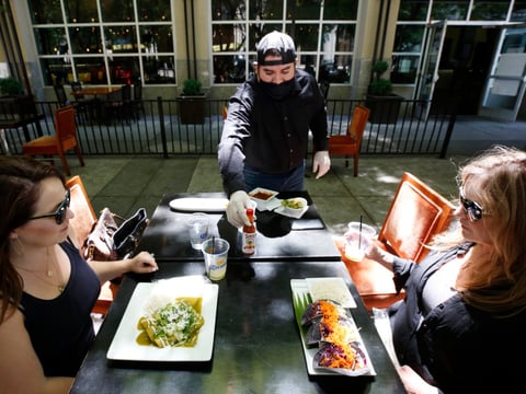 Jesus Rodriguez brings hot sauce to diners Jennifer, left, and Tracy Kniesel at the Tequila Museo Mayahuel restaurant in Sacramento, Calif., Friday, May 22, 2020.