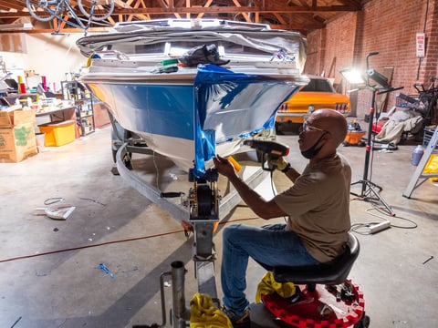 Kevin Lash applies a vinyl wrap to a boat at his shop, Wrapalot Specialty Films in Sacramento, Tuesday, July 14, 2020.