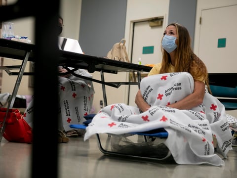 Shawnee Whaley, 57, wears a mask as she rests on a cot at the Ulatis Community Center in Vacaville after evacuating her home on August 18, 2020.