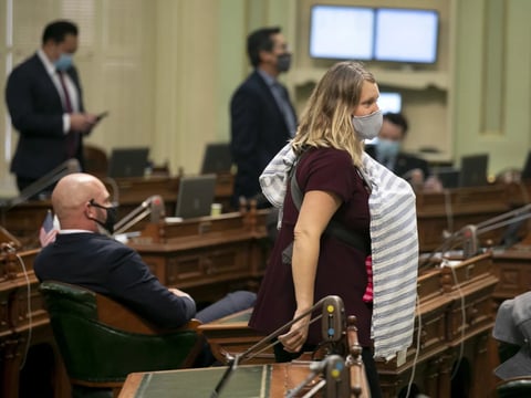 Assemblymember Buffy Wicks walks across the floor during a vote carrying her 1-month-old baby on Aug. 31, 2020. Wicks was not permitted to vote remotely despite having a newborn.
