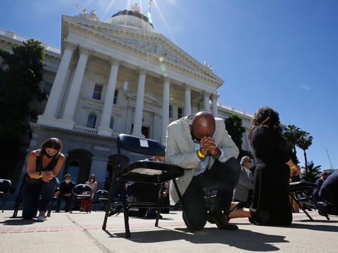 Assemblyman Mike Gipson, D-Carson, bows his head as he and other members of the California Legislature kneel for 8 minutes and 46 second to honor George Floyd at the Capitol in Sacramento, Calif. Tuesday, June 9, 2020.