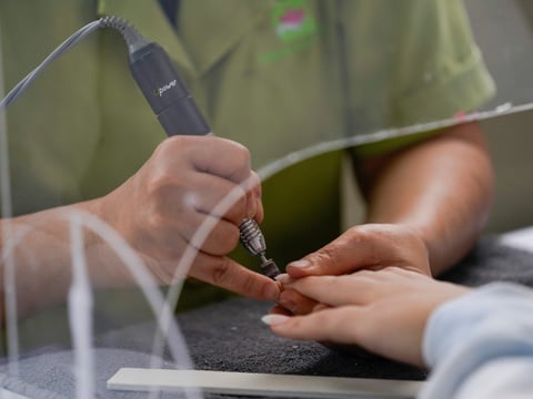 A beauty saloon employee works on a customer's nails from under a plexiglass shield outside Pampered Hands nail salon on Wednesday, July 22, 2020, in Los Angeles.