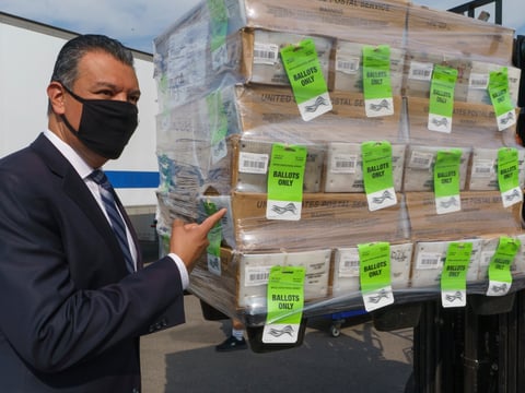 California Secretary of State Alex Padilla stands next to a pallet with voting ballots, after a news conference on Orange County's comprehensive plans to safeguard election and provide transparency in Santa Ana, Calif., Monday, Oct. 5, 2020.