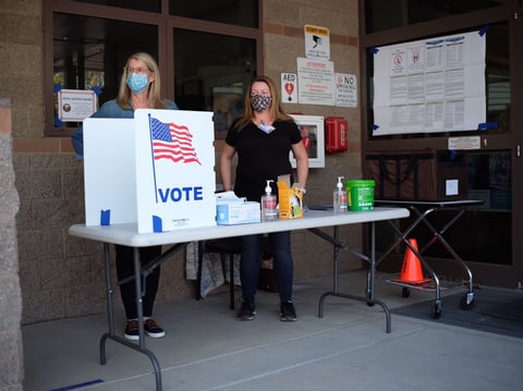 Election officials Jill Nall and Heather Hurtt stand beside an outdoor ballot booth at the Fire Station 85 voting center in El Dorado Hills.