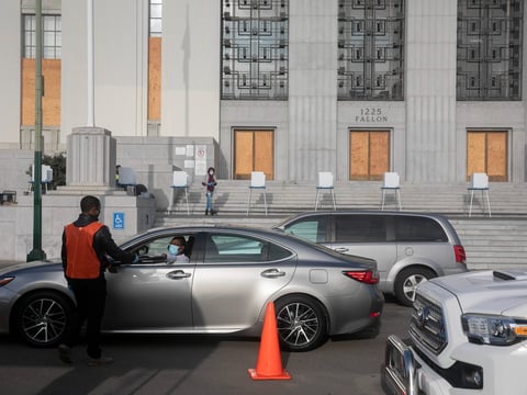 Drivers line up to drop off ballots outside of a boarded up Alameda County courthouse on Nov. 3, 2020.