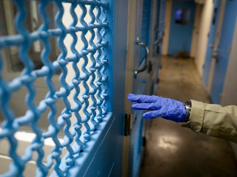 A gloved hand points to a holding cell at the hospital ward of the Twin Towers jail in Los Angeles on April 16, 2020.