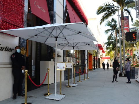 A security guard in a face mask stands outside Cartier jewelry shop with no customers in line during the coronavirus pandemic on Rodeo Drive, Thursday, Dec. 3, 2020, in Beverly Hills, Calif.
