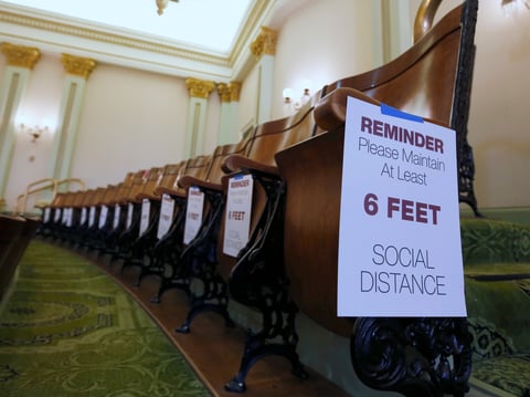 In this May 4, 2020 file photo signs posted in the Assembly gallery remind visitors to stay 6 feet apart, at the Capitol in Sacramento, Calif.