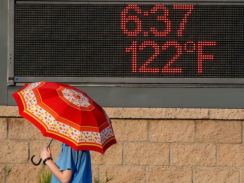 A pedestrian uses an umbrella to get some relief from the sun as they walk past a sign displaying the temperature on June 20, 2017 in Phoenix, Arizona. As 2020 comes to a close so does the hottest recorded decade.