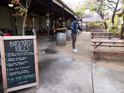 Zach Erickson measures to make sure tables are socially distanced at Hop Garden Wednesday, Jan. 13, 2021.