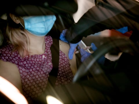 Health care workers receive COVID vaccinations at a drive-through distribution site at Cal Expo in Sacramento on Jan. 21, 2021.