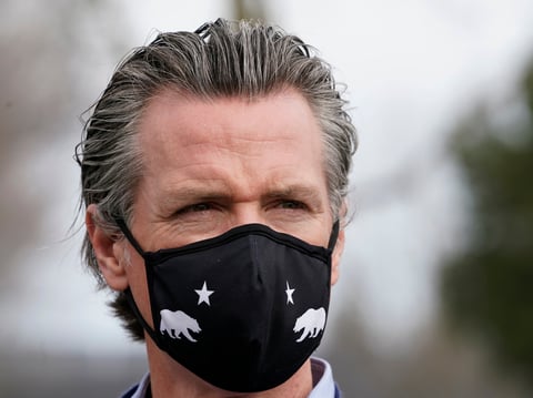 Gov. Gavin Newsom wears a face mask during a visit to a drive-thru COVID-19 vaccination center at Natomas High School in Sacramento, Calif., Thursday, Feb. 11, 2021.