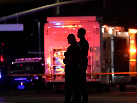 Two police officers stand outside an office building where a shooting occurred in Orange, Calif., Wednesday, March 31, 2021.