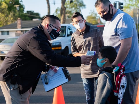 Program Manager Ryan Saechin checks Luke Henley's, 5, temperature before allowing him onto campus at John Cabrillo Elementary School, Thursday, April 8, 2021.