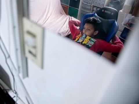 Mario Ramírez Garcia, 10, listen as his teacher addresses the class during distance learning in the bedroom he shares with his sister on April 23, 2021.